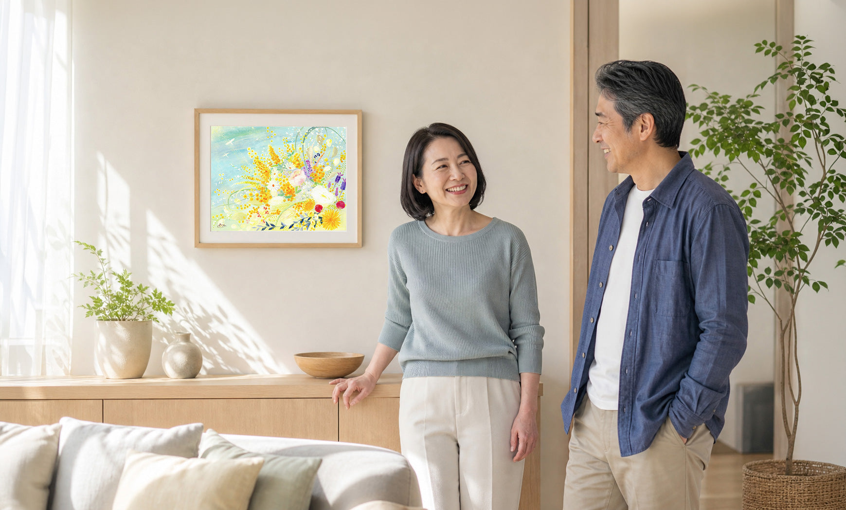 明るいリビングで作品のそばに立つ二人