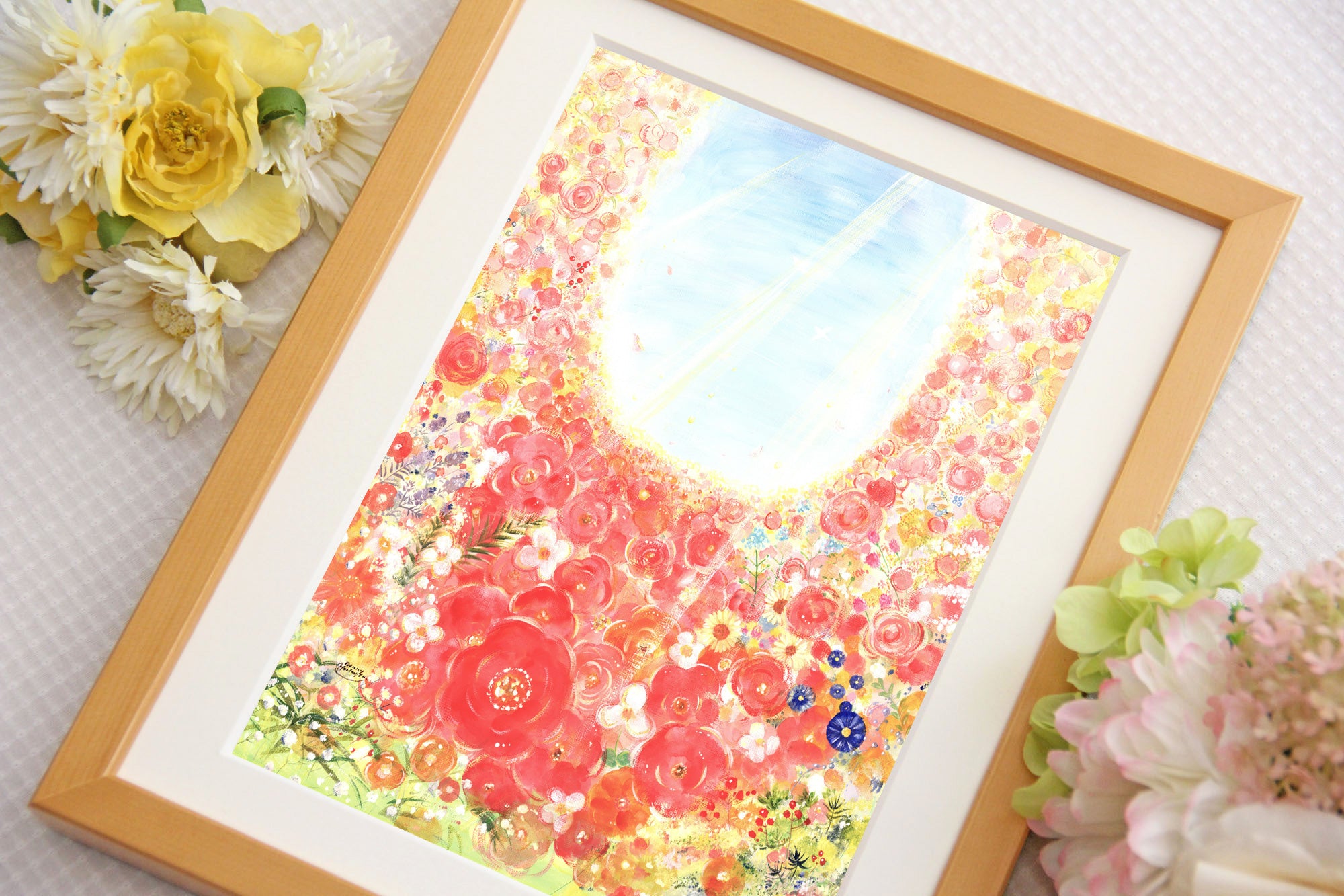 赤や黄色の花々を描いた作品を、花とともに飾った写真