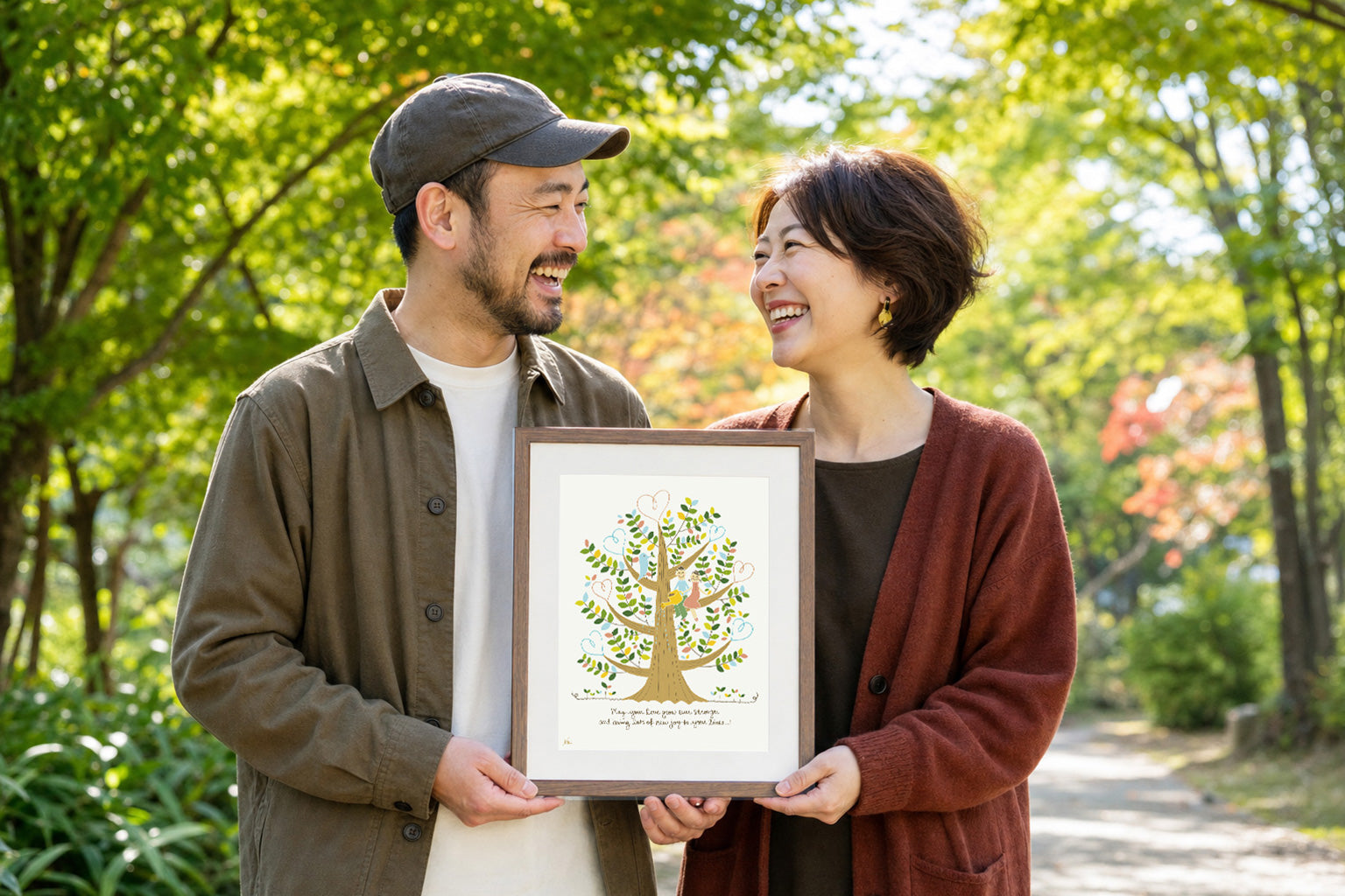 夫婦が公園でしあわせの樹を手に笑い合う結婚記念日の贈り物の場面