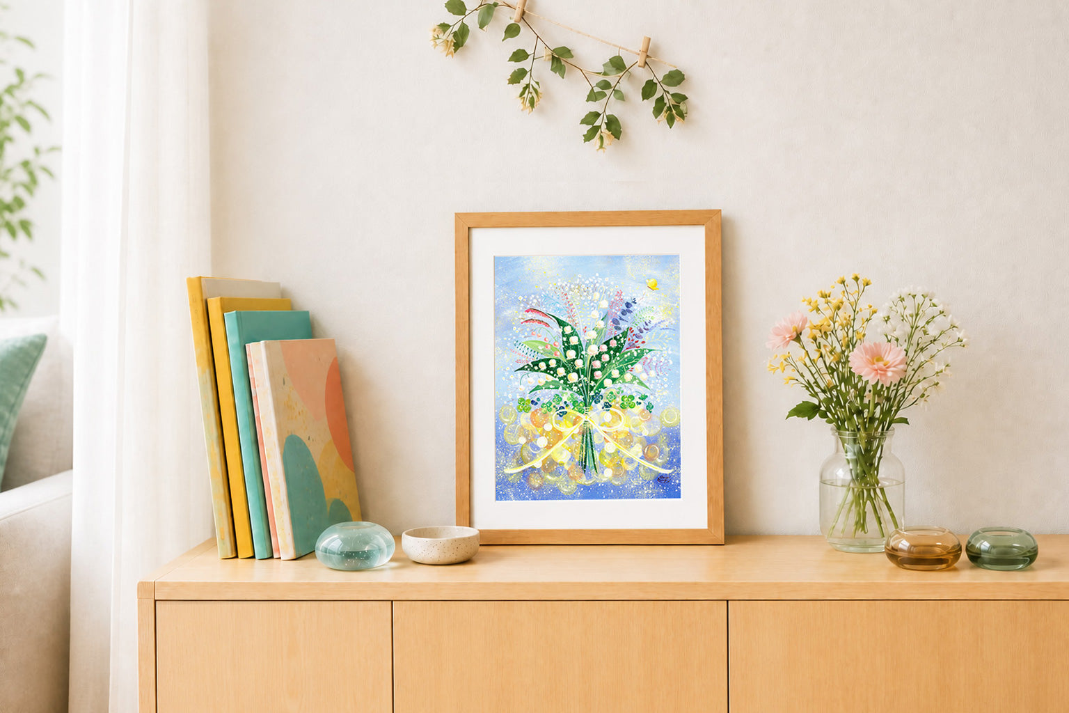 明るいリビングの棚にすずらんの花束を描いた額装作品を飾った様子
