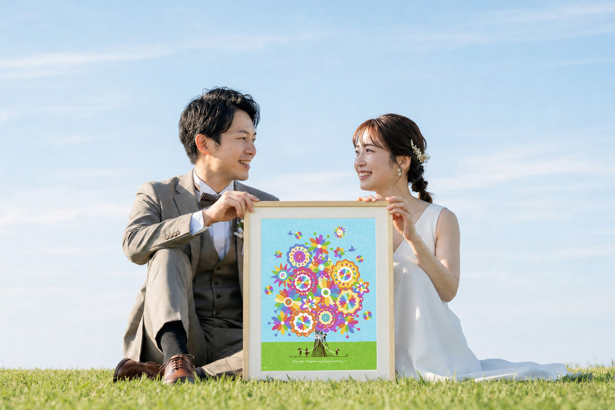 前撮りで新郎新婦が結婚祝いの額装作品を手に微笑む様子