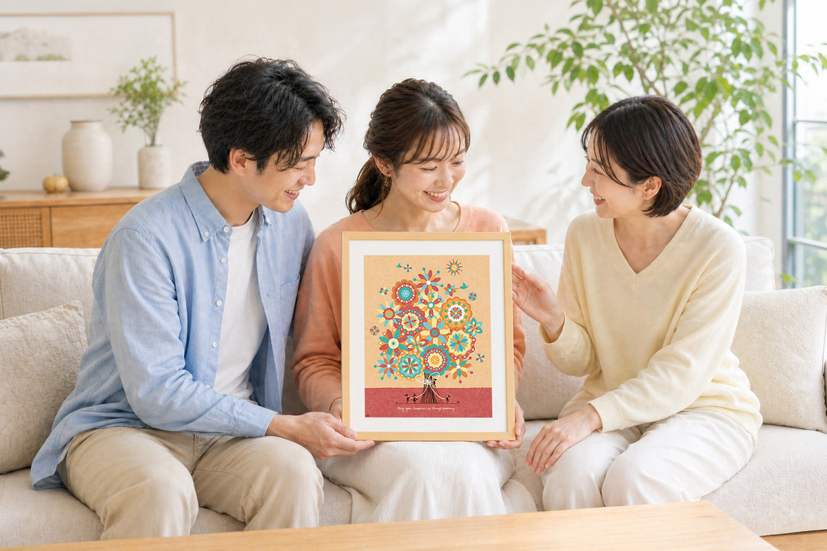 友人から結婚祝いの額装作品を受け取り、笑顔を見せるふたり