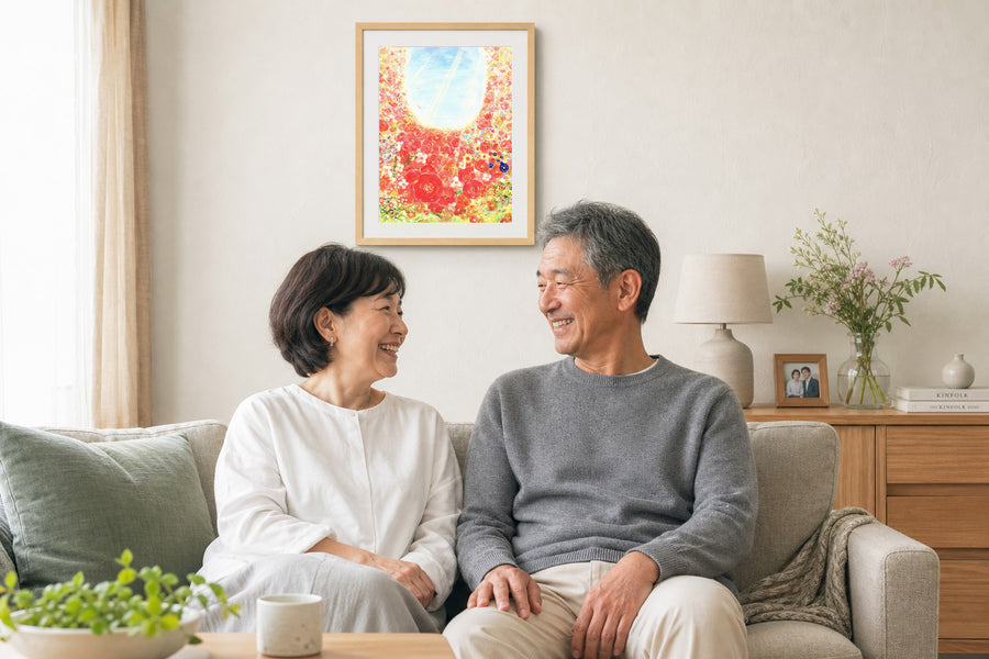 リビングの壁に花の絵を飾り、ソファで笑顔を交わすご夫婦