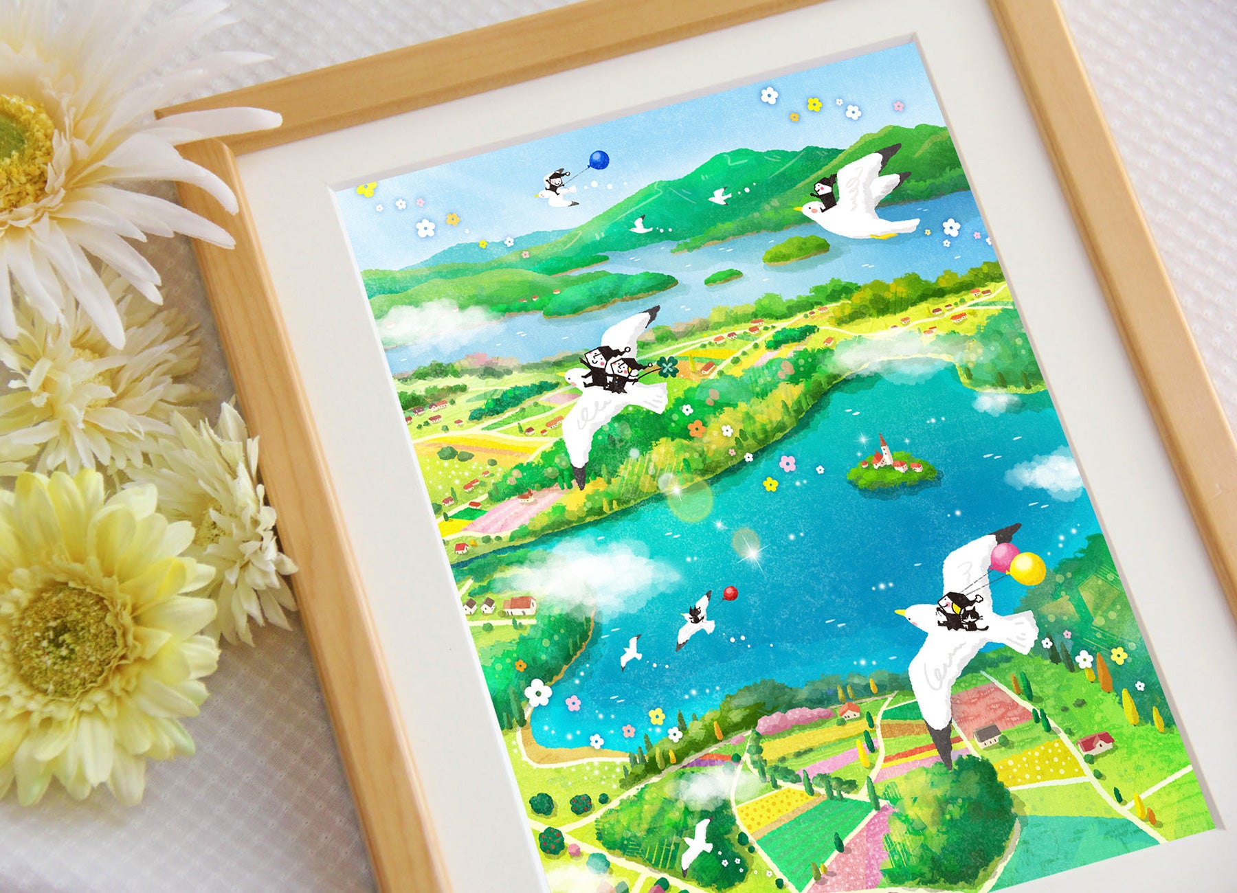 青い湖と緑の風景を白い鳥が渡る「Bon Voyage!」を額に入れて飾った写真