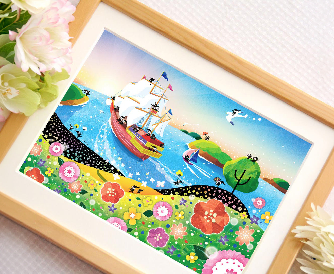 青い海を進む帆船と花々を描いた「輝きの朝」を額に入れて飾った写真